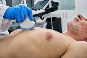 Heart health check-up with ultrasound scan machine. Heart ultrasound exam for elderly man with...
