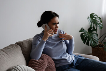 Portrait of irritated young woman arguing on phone. Outraged female talking angrily, shouting at cellphone. Customer support frustration concept. Copy space for text, white wall background, close up.