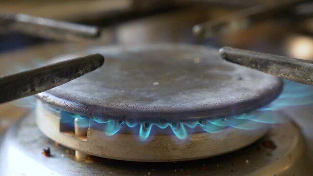 Old rusty kitchen gas oven top burner stove, fire starting, close up.