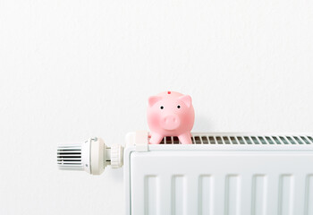 save heating costs, piggy bank on heating radiator, white background