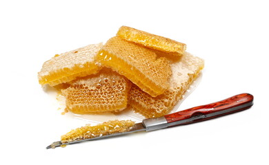 Yellow honeycomb with honey and knife isolated on white