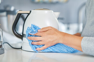 Young woman cleaning kettle in the kitchen