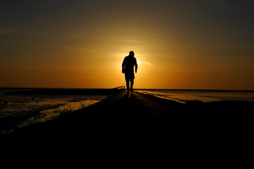 Fototapeta na wymiar Silhouette of a man goes to meet the sunset.