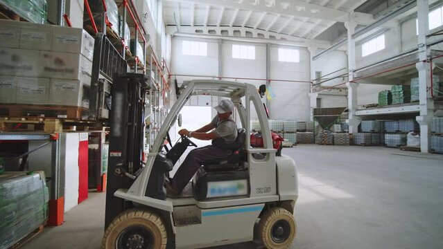Professional Driver Operates Forklift Truck With Cargo In Big Warehouse
