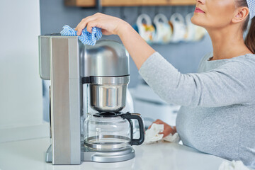 Young woman cleaning coffee pot or machine