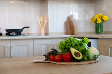 Bunch of different raw organic fruits, vegetables and greens lying in pile on a chopping board. Kitchen table with groceries. Close up, copy space for text, interior background.