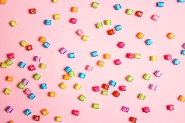 Colorful letter beads on pink background. Flat lay.