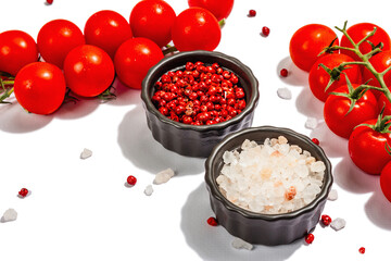 Cooking background with tomato cherry, sea salt, and rose peppercorn isolated on white background