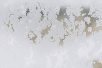 Wintry frosty pattern on glass. Abstract background of ice frozen window. Incredibly beautiful patterns are drawn by a frost on the windows of houses