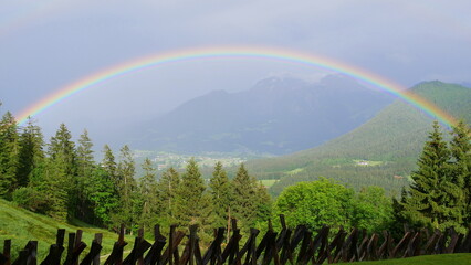 Halbkreisförmiger Regenbogen in einem Bergtal
