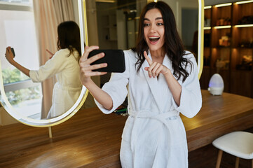 young beautiful girl in a beauty salon in a white coat makes a selfie. Bride's morning concept