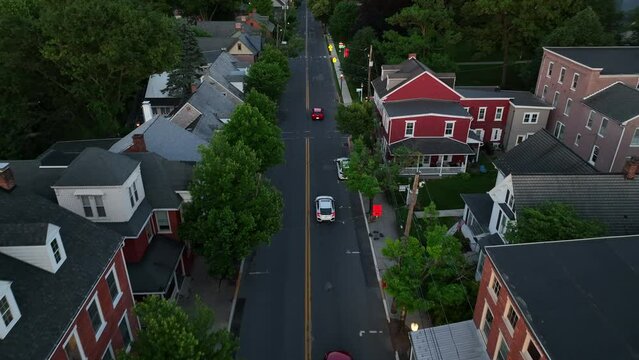 Aerial tracking shot of Honda Civic sedan. Cars drive in small town America at dusk during spring.