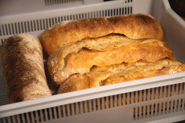 Fresh crispy hot delicious craft artisan bread. Many loaves lie on a wooden pallet