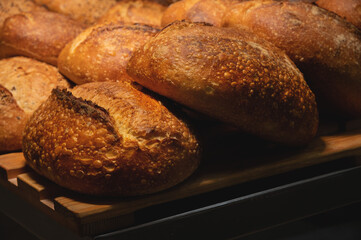Fresh crispy hot delicious craft artisan bread. Many loaves lie on a wooden pallet