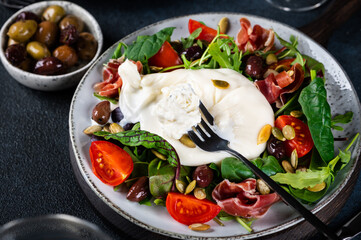 Burrata, Italian fresh cheese made from cream and milk of buffalo or cow. Burrata salad with tomatoes and salad mix. Healthy eating concept. Keto diet salad.