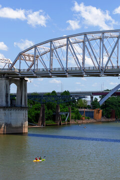 Kayakers paddling under the John Seigenthaler Pedestrian Bridge on the Cumberland River in Nashville, Tennessee.. Photographer Derek Broussard