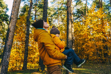 Father and son in autumn forest. Profile view.