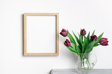 Wooden portrait frame mockup with tulips flowers over white wall
