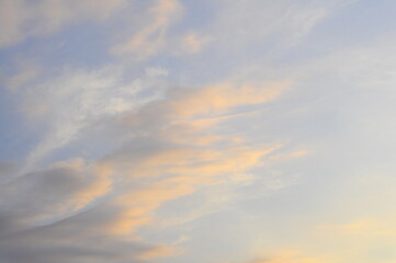 Background of evening sky, light stretched clouds in the sun. Sky with a gradient of color from warm to cold