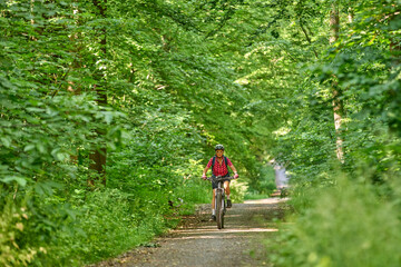 Obraz premium nice active senior woman riding her electric mountain bike in the green city forest of Stuttgart, Germany