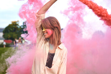Caucasian woman dancing with coloured smoke bombs at Holi Festival