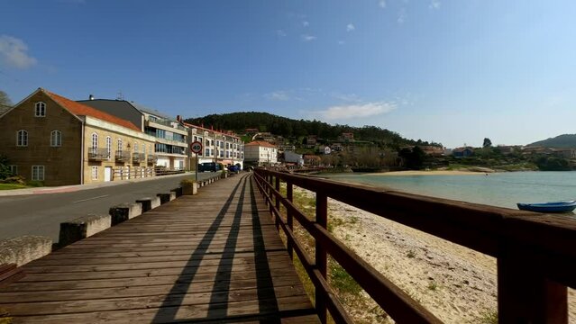 Wooden promenade by beautiful peaceful Aldan beach with canoeist on background