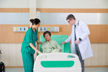 Elderly woman patient on hospital bed and man doctor with nurse. doctor talking consulting and checkup by stethoscope with patient. Hospital Healthcare and medicine concept.