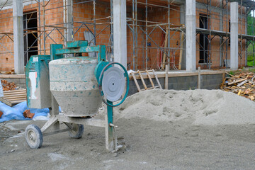 Concrete mixer in a site close-up. construction site with equipment and building. House in...