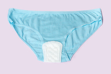 Women's blue underwear and white padding on a pink background. Women's health concept. Women's...