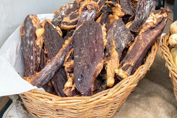 Pieces of homemade beef jerky in basket at farmers market. Close-up on tasty jerky meat snack.