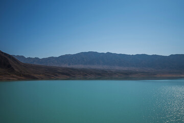 Obraz premium Lake with mountains on the background. Mountain range view. A sultry haze over desert mountains and a salty turquoise lake.