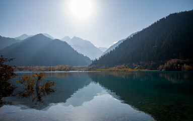 Serenity lake in the mountains. Foggy autumn morning with mountains and reflection.