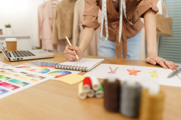 Fototapeta na wymiar Fashion design concept, Asian female fashion designer sketching new clothes collection in atelier