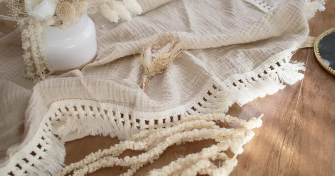 Slow motion view of deranged table decor like a beige muslin cloth, vintage flower pot and a mirror.