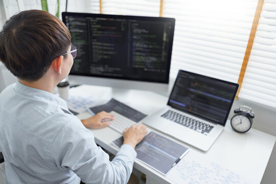 Software development concept, Male programmer typing data code and working on multiple screens