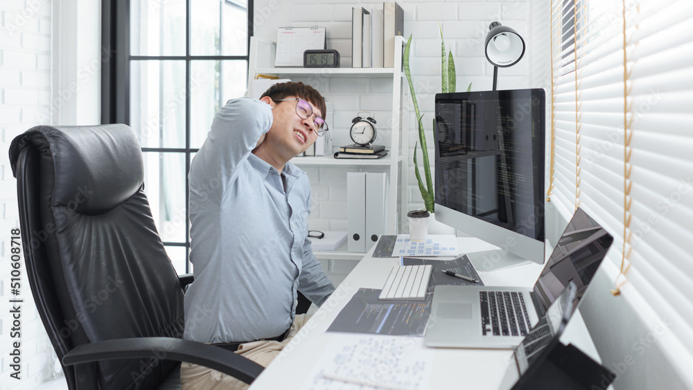 Wall mural software development concept, male programmer suffering neck pain after working hard on computer