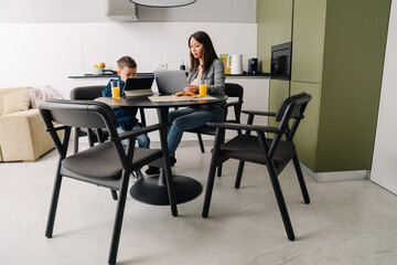 Happy young asian woman having breakfast with her little son at home