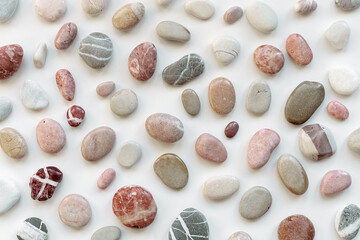 Top view close up sea stones on light background. Colorful pebbles as summer pattern. Natural stone white red pink grey colors. Minimal flat lay, background with natural materials