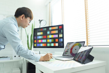 Fototapeta na wymiar Creativity concept, Male graphic designer choosing color swatch samples on document and designing