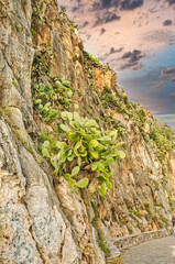 Stone path along the sea coast on sunset with rocky cliff on the side and blue sky near Nafplio cit