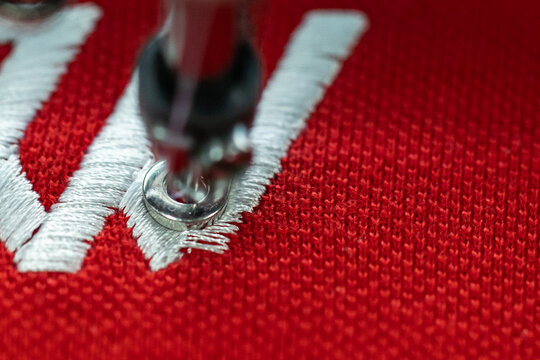 extreme close-up of embroidery needle with thread sewing on T-shirt material