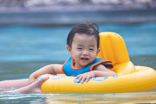 Portrait image of​ 1-2 years old​ childhood​ child happy and enjoying playing water on pool