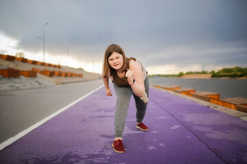 European teenage girl overweight on jog on treadmill along embankment of city, overweight and active lifestyle of teenager