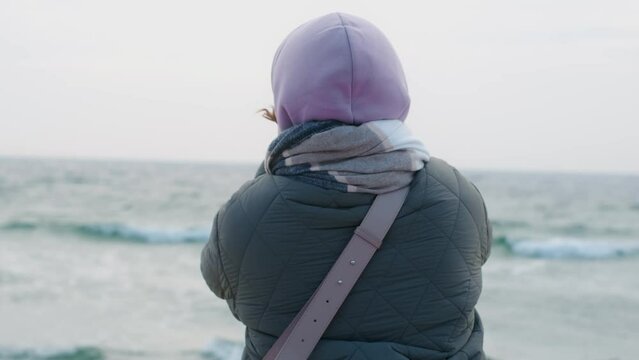 Woman blogger in warm clothes does selphie on the winter beach. Traveller at the cold sea in the off-season, 4k 60p