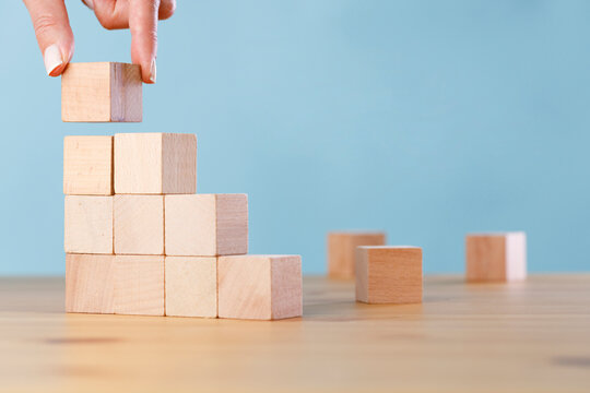 Woman hand arranging wood block stacking. Business concept for growth success process