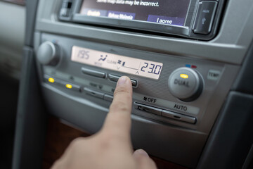 Man hand press and adjust Air conditioner control in luxury car interior