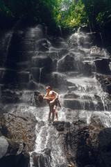 Fototapeta premium Couple stand under a large waterfall