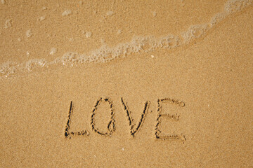 LOVE - handwritten on the soft beach sand.