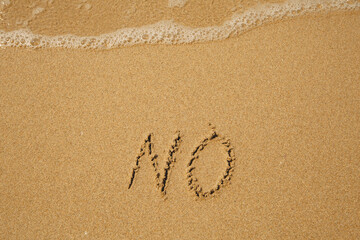 No - handwritten on the soft beach sand.