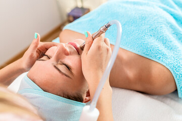 Beautician therapist applying face treatment in beauty salon to young woman.